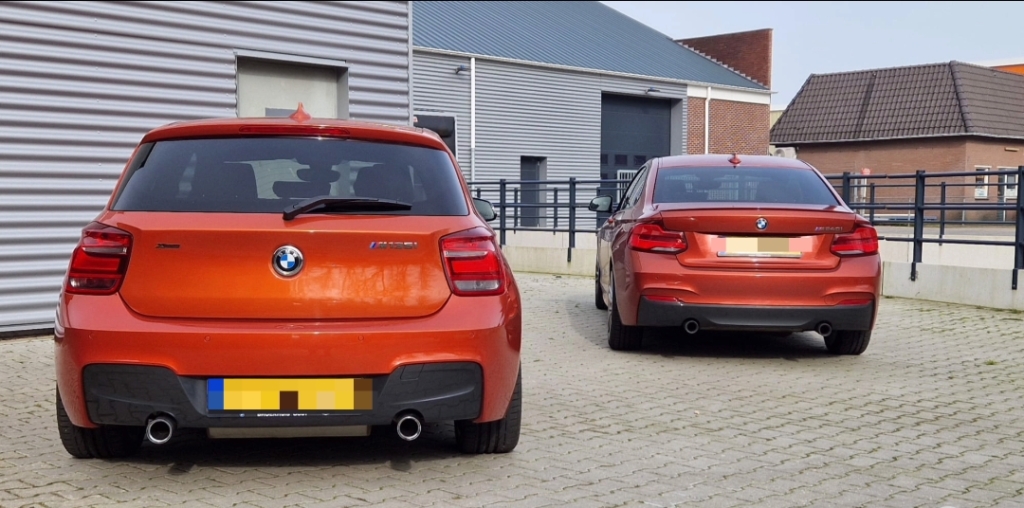 Oranjekleurige BMW M135i naast oranjekleurige BMW M240i